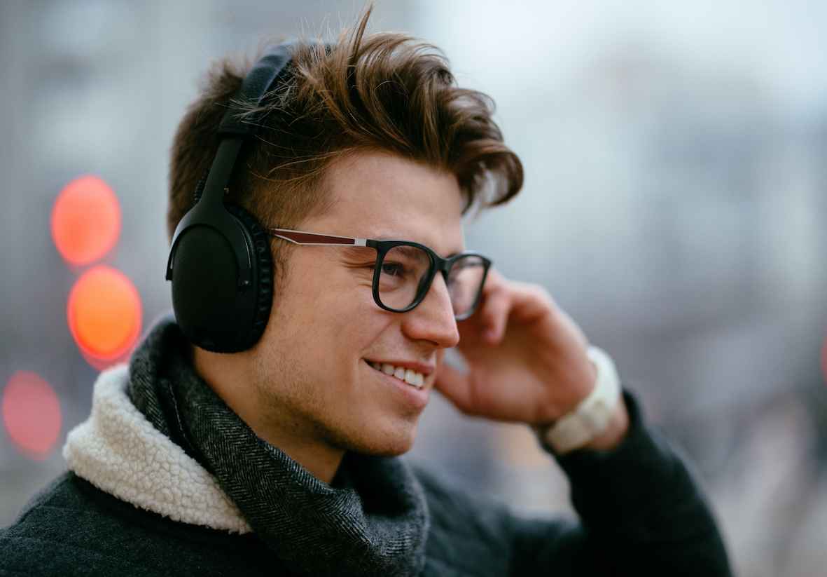 Cheerful man enjoying listening to music in headphones, outdoors