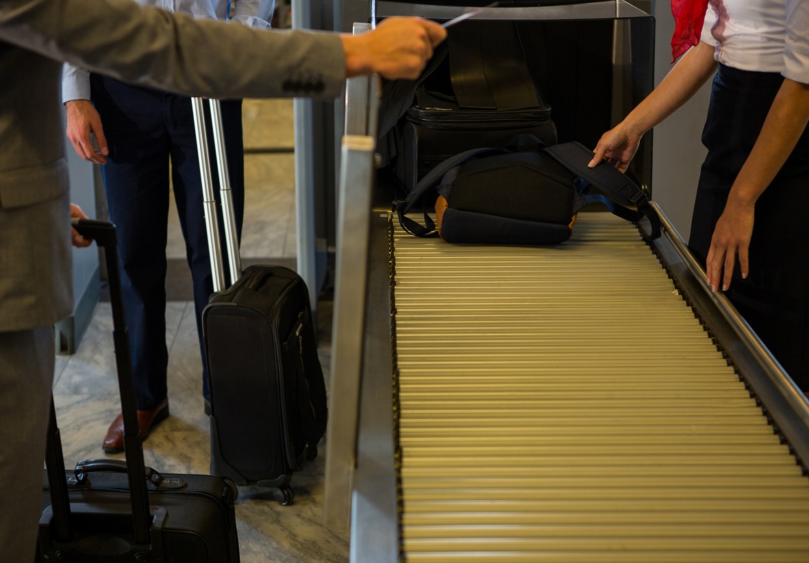 Female staff checking passengers luggage on conveyor belt in airport