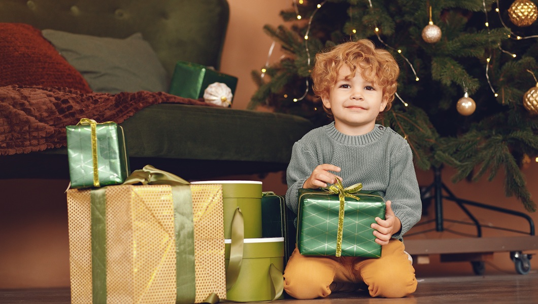 Little boy near christmas tree in a gray sweater
