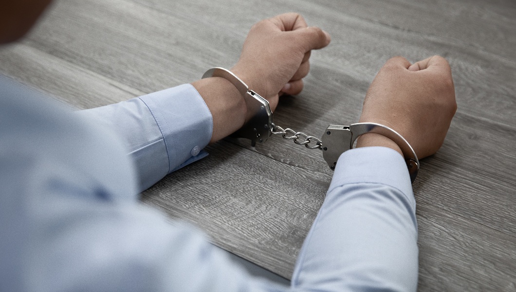 Selective focus shot of male hands in handcuffs on a wooden table