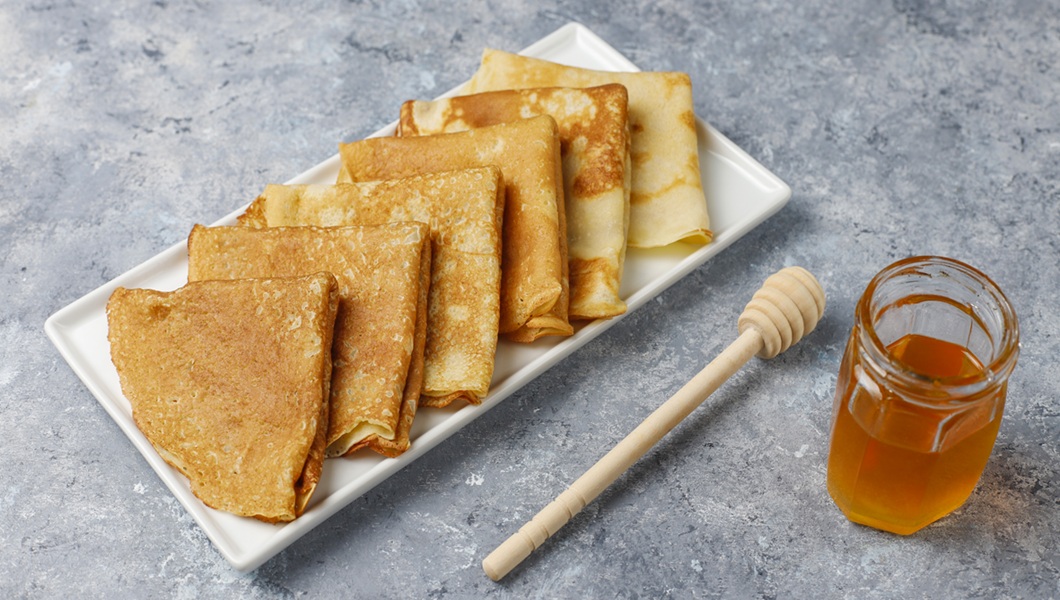 Delicious Breakfast on light background. Orthodox holiday Maslenitsa. Crepes with cumquats and honet,top view
