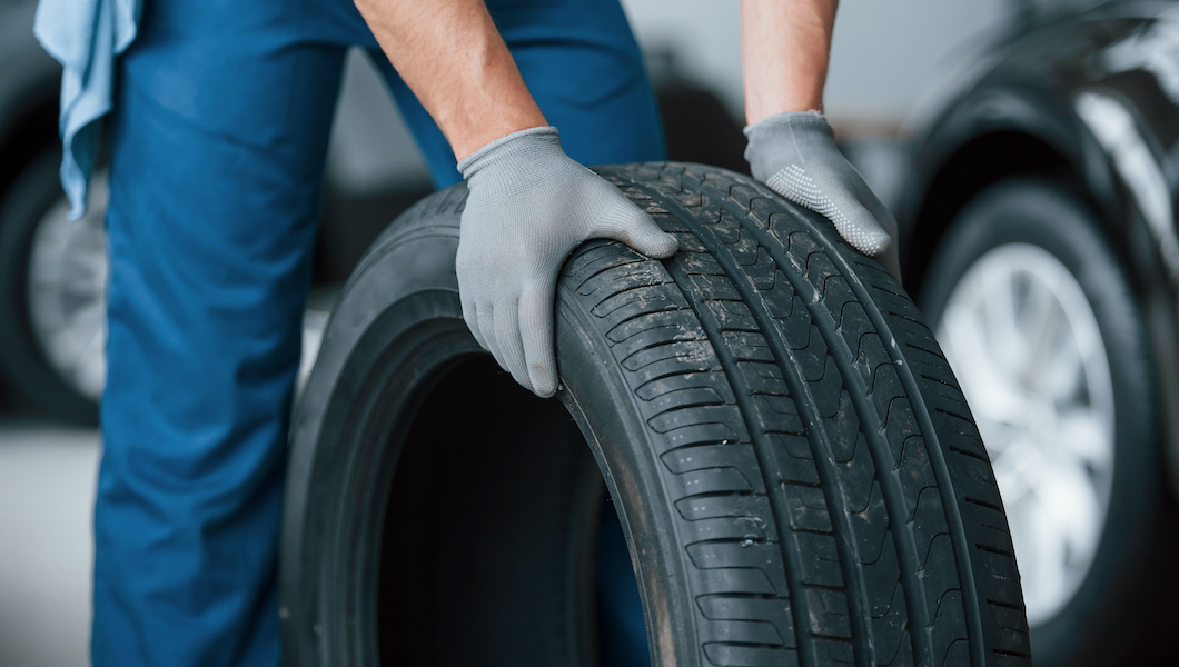 One more improvement and job will be done. Mechanic holding a tire at the repair garage. Replacement of winter and summer tires
