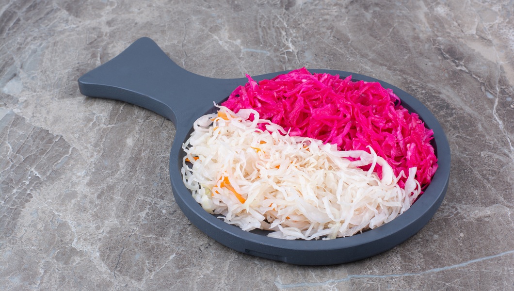 Sauerkraut and red cabbage on black wooden board