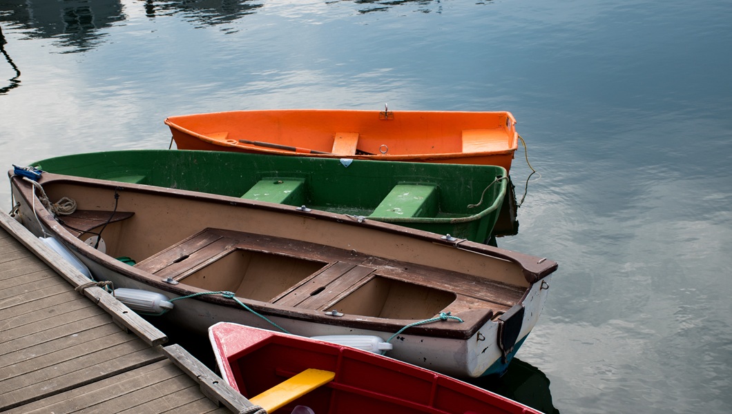 Beautiful scene of four colorful boats in next to the wooden shore of the lake